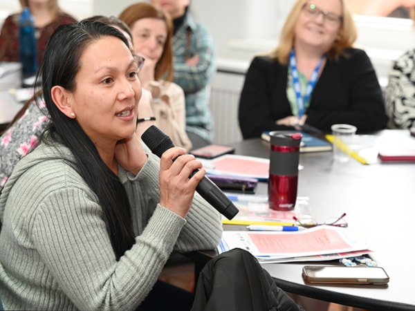 Member at meeting table holding microphone 